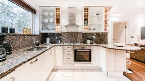 A modern kitchen with granite countertops, white cabinets, and a built-in oven. - My Lady (London)