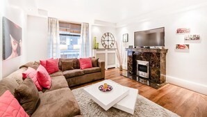 A modern living room with a brown sofa, a white coffee table, a fireplace, and a TV. - My Lady (London)