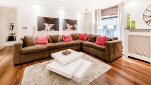 A modern living room with a sectional sofa, white coffee tables, and artwork on the wall. - My Lady (London)