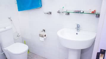 Ein Badezimmer mit Toilette, Waschbecken und Toilettenpapier an der Wand.