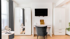 Un dormitorio moderno con un armario grande, un escritorio con televisor y un espejo.