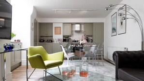 Une cuisine moderne avec un coin repas, comprenant une table en verre, une chaise verte et un canapé noir.