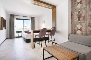 A modern hotel room with a bed, a desk with two chairs, a sofa, and a balcony with a view. - Stic Urban Hotel & Spa (Sant Antoni de Portmany)