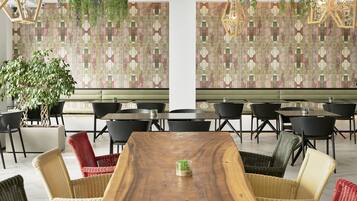 A dining area with a wooden table, wicker chairs, and a patterned wall.
