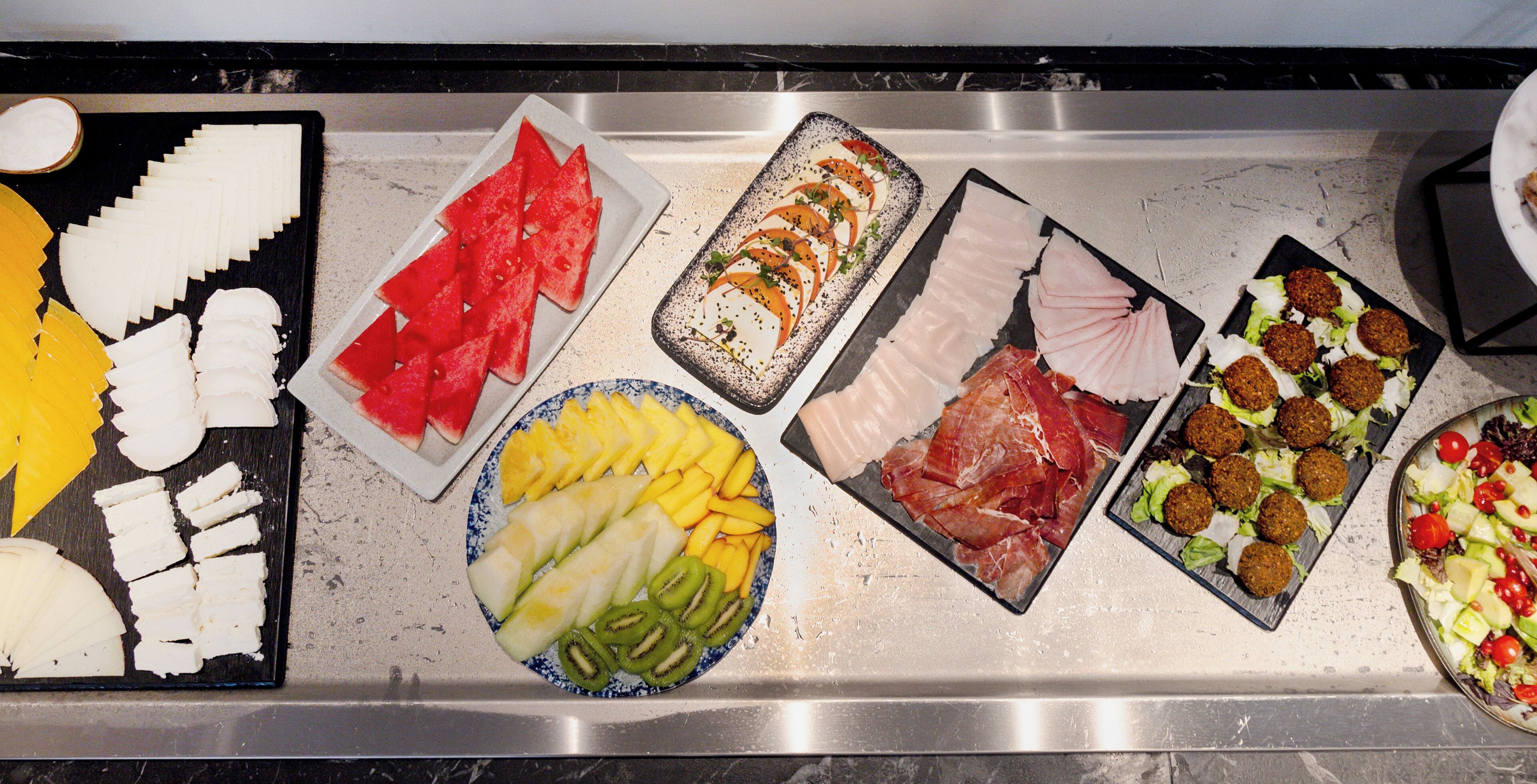 A buffet with various food options including fruits, meats, and salads.