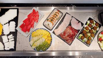 A buffet with various food options including fruits, meats, and salads.
