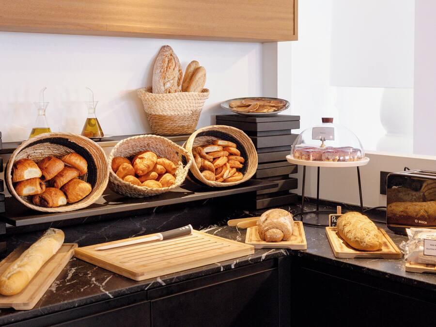 A bakery display with various breads and pastries on a marble countertop.