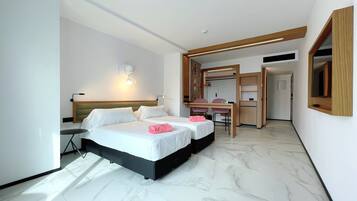A hotel room with a bed, bedside tables, a desk, and a chair.
