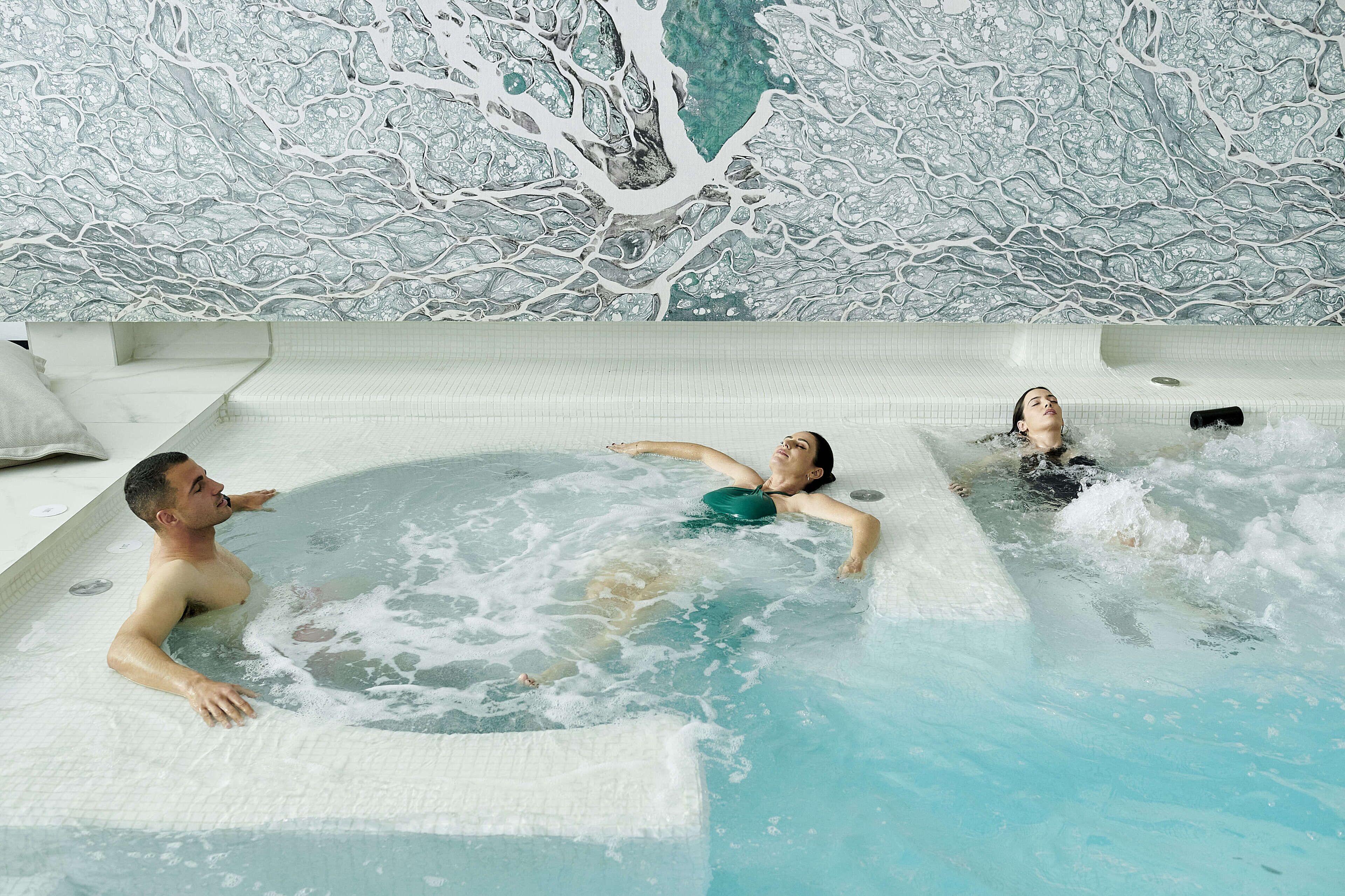 Een wellnessruimte met een ruime hottub en een muurschildering.