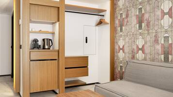 Une chambre moderne avec une armoire en bois, un canapé gris et un papier peint à motifs.