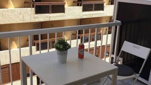 A balcony with a table, chairs, a potted plant, and a can. - Downtown beach & peace (Málaga)