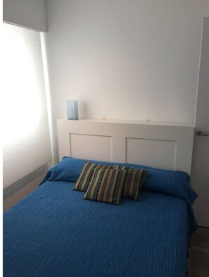 A bedroom with a bed, a window, and a door.