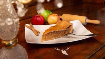 Ein Stück Kuchen auf einem weißen Teller mit Zimstangen daneben, auf einem Holztisch platziert.