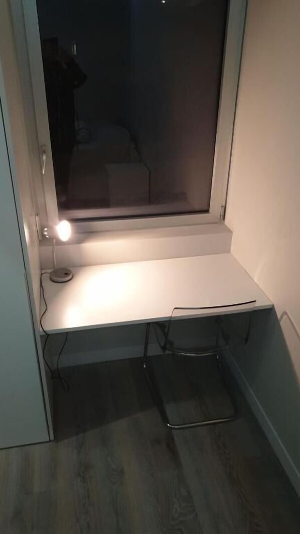 A small, enclosed room with a desk and a chair, a window, and a door.