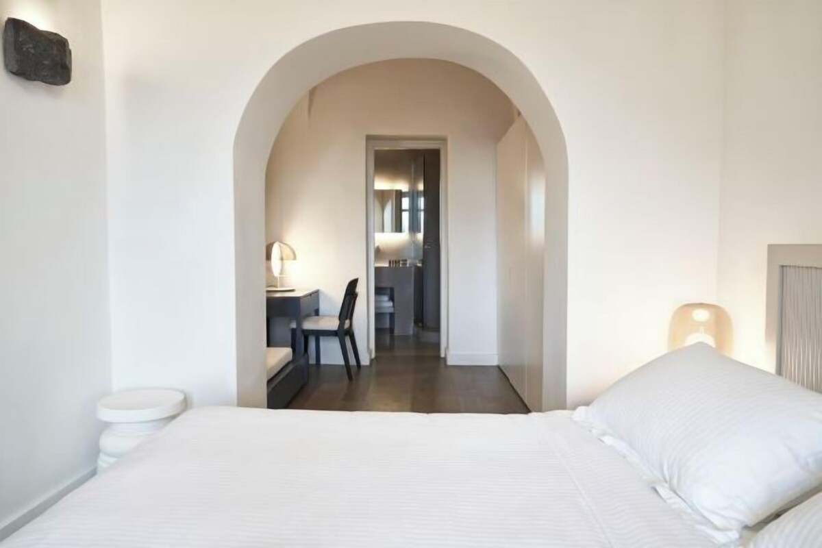 Une chambre d’hôtel avec un grand lit, un bureau avec une chaise et une salle de bain visible.
