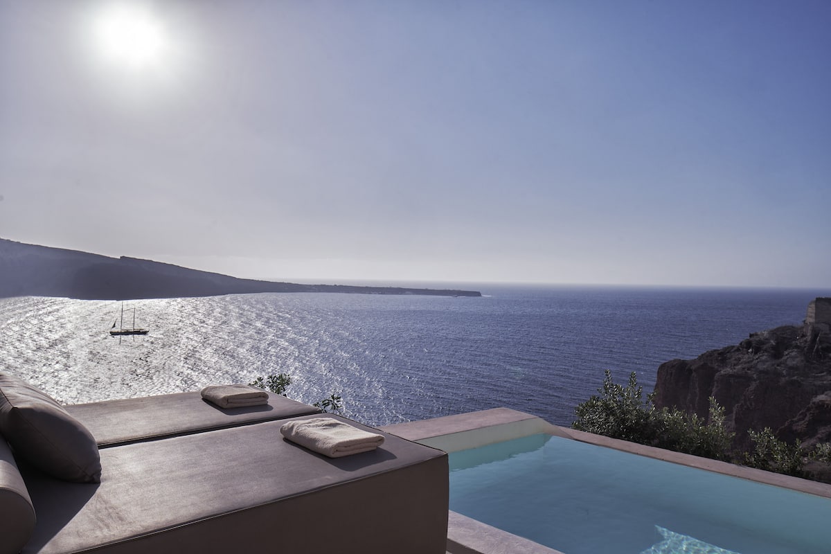 A poolside area with lounge chairs and a view of the ocean.