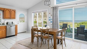 A kitchen with wooden cabinets, a dishwasher, and a dining area with a table and chairs. - 6 Bedroom House, Ocean View, A/C, One Floor, Less than 1 Mile to Beach (Narragansett)