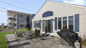 A two-story house with a patio area featuring a table and chairs, a covered grill, and a propane tank. - 6 Bedroom House, Ocean View, A/C, One Floor, Less than 1 Mile to Beach (Narragansett)