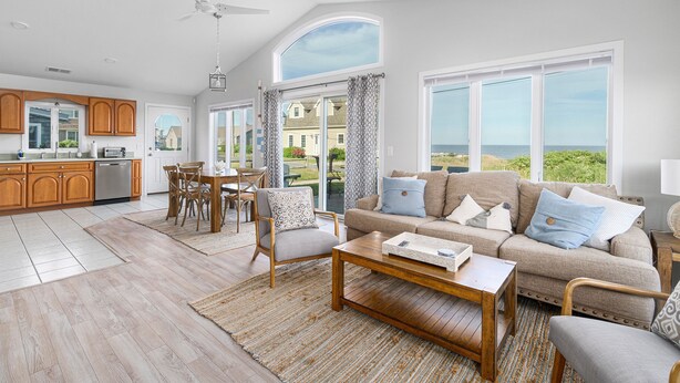 A spacious living area with a large window, a dining table, and a kitchen in the background. - 6 Bedroom House, Ocean View, A/C, One Floor, Less than 1 Mile to Beach (Narragansett)