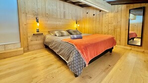 A wooden bedroom with a bed, two bedside lamps, a mirror, and a window. - Quiet apartment near slopes, 6 ppl, parking (Notre-Dame-de-Bellecombe)