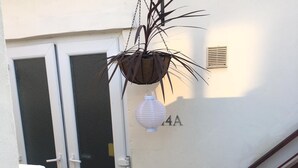 En vit dörr med ett glasparti, en liten krukväxt och en vit papperslykta.