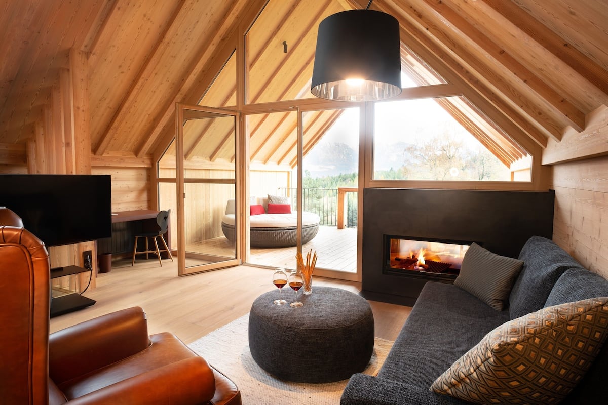 Un salon chaleureux avec une cheminée, un canapé en cuir, un pouf et un téléviseur.