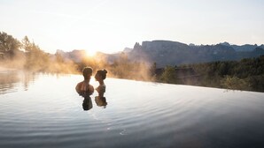Piscina infinita al aire libre, tranquila, con vistas claras a montañas y un amanecer.