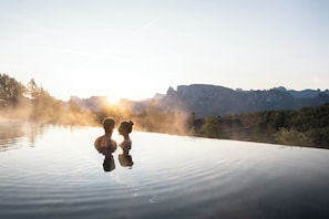 Piscina infinita al aire libre, tranquila, con vistas claras a montañas y un amanecer.