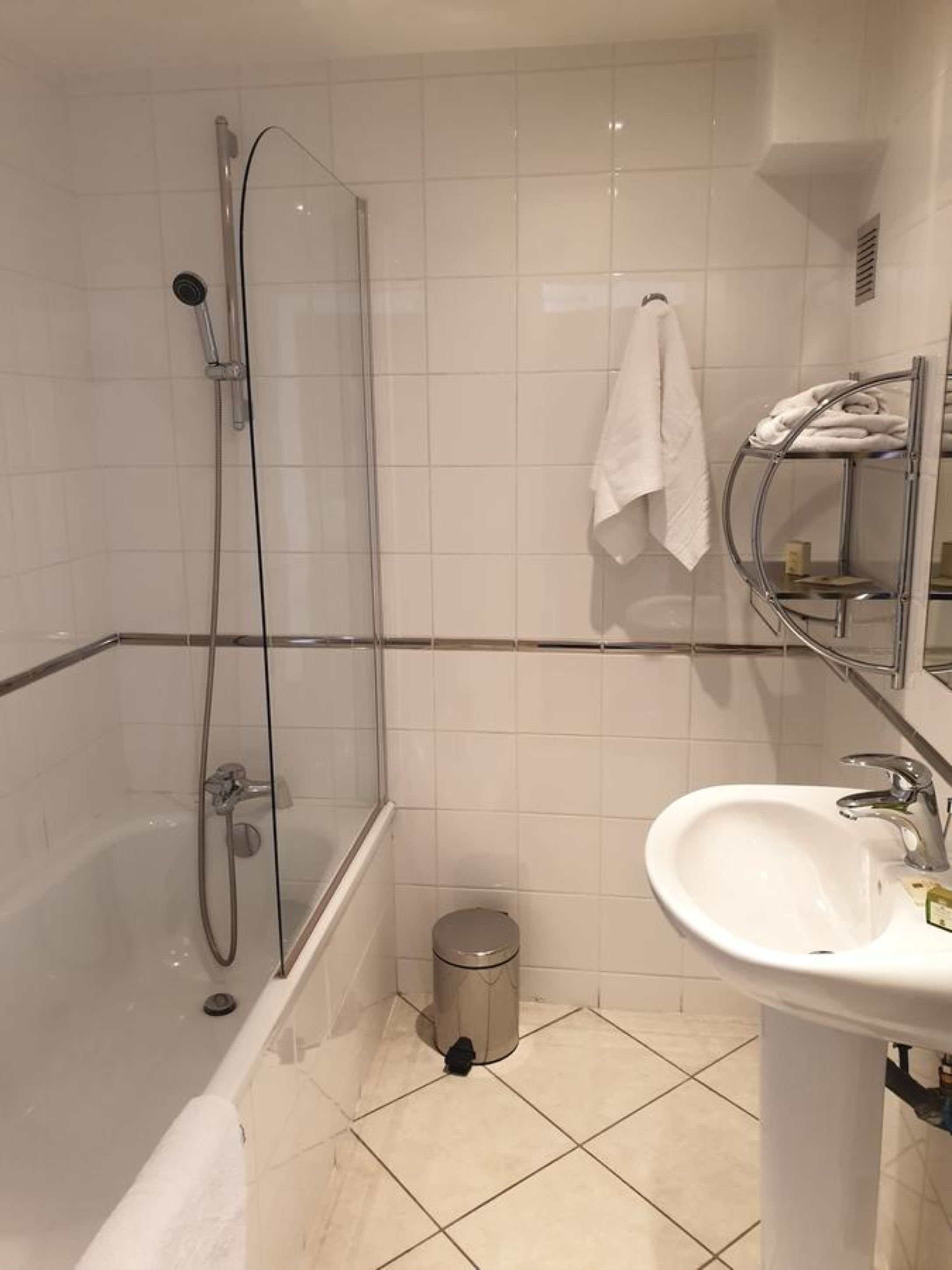 A modern bathroom with a glass-enclosed shower, a white sink, and a towel rack.