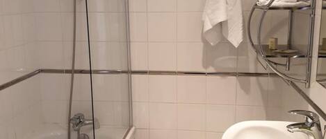 A modern bathroom with a glass-enclosed shower, a white sink, and a towel rack.