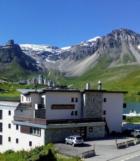 Hotel con vista a la montaña, un cartel que dice 'La Capella' y un estacionamiento con coches.