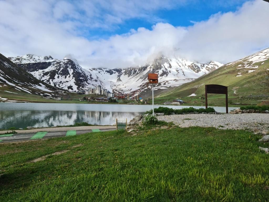 A mountain landscape with a lake, a viewing platform, and a small building.