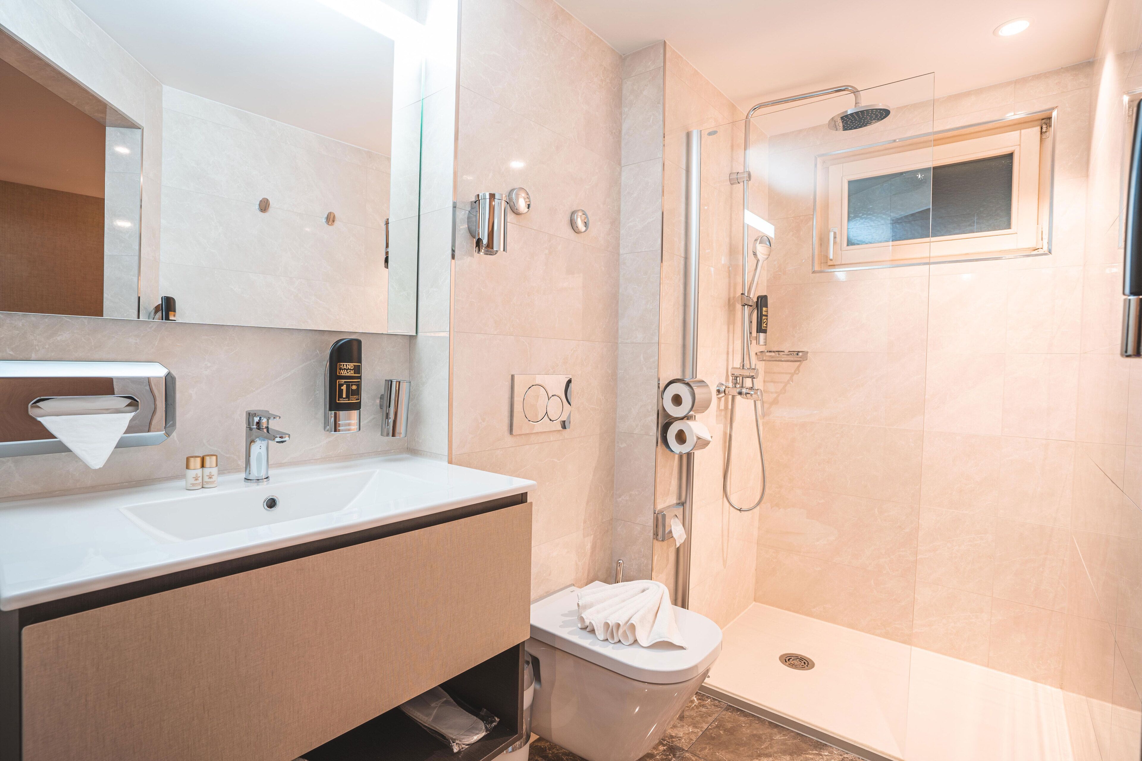 A modern bathroom with a sink, mirror, toilet, and shower.