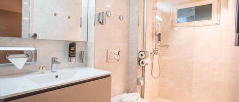 Un baño moderno con lavamanos, espejo, inodoro y ducha.