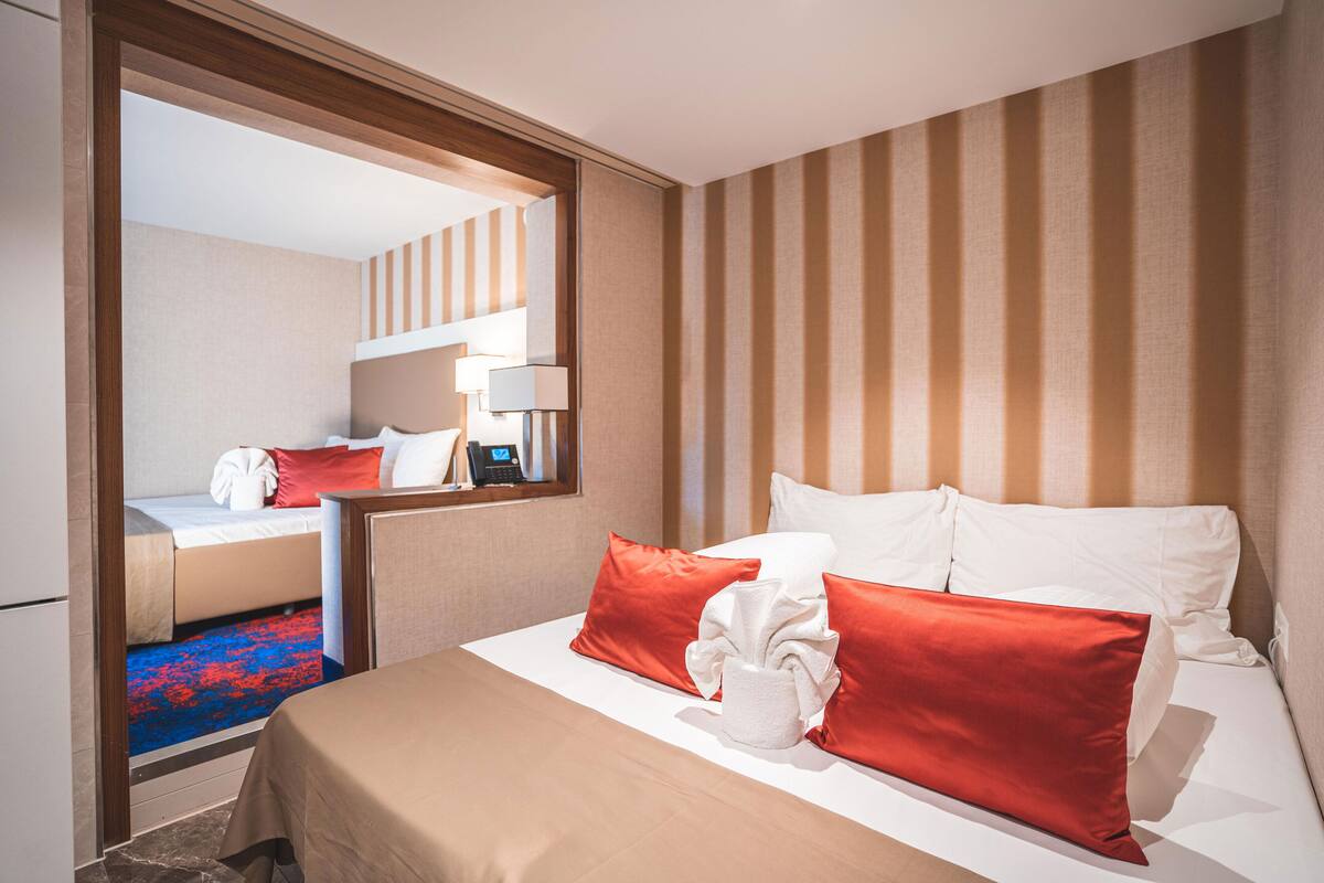 A hotel room with a bed, a desk, and a mirror.