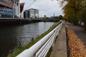 A riverside walkway with a concrete barrier, a bridge, and modern buildings in the background.