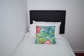 A bed with white bedding and a black headboard, featuring a single colorful pillow with a tropical print. - Luxury Apartment - Central Cardiff (Cardiff)