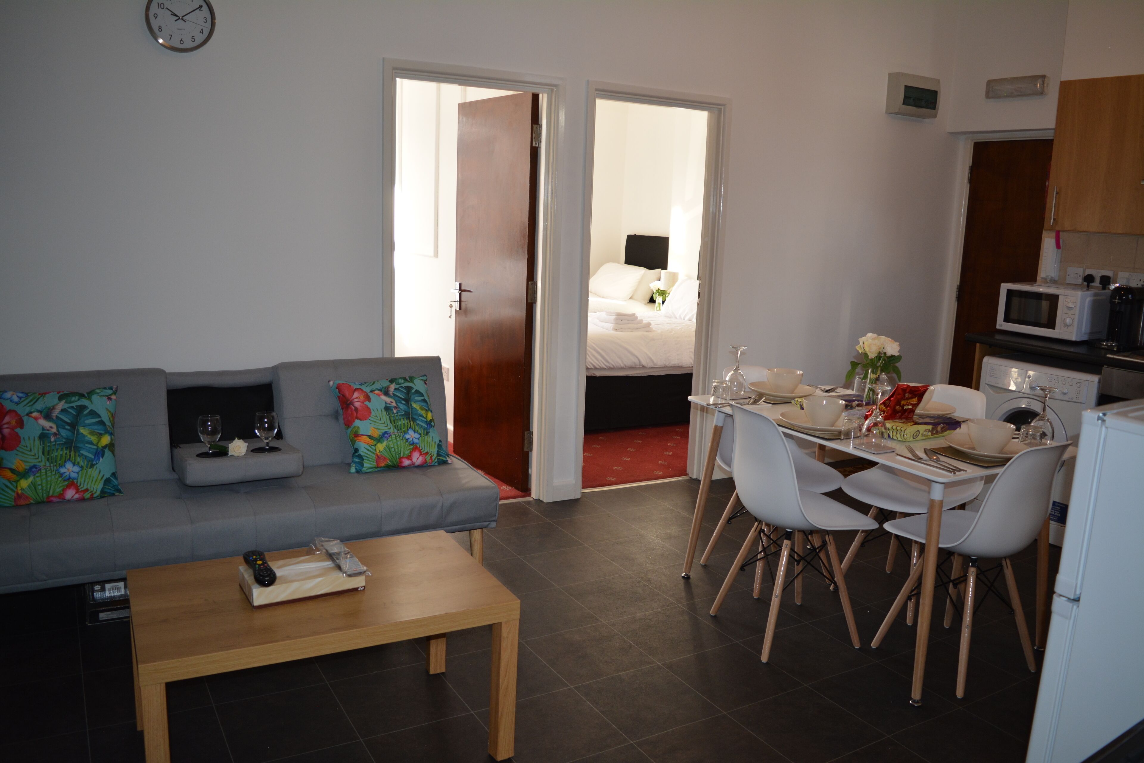 A compact living space with a sofa, dining table, chairs, and a kitchen area.