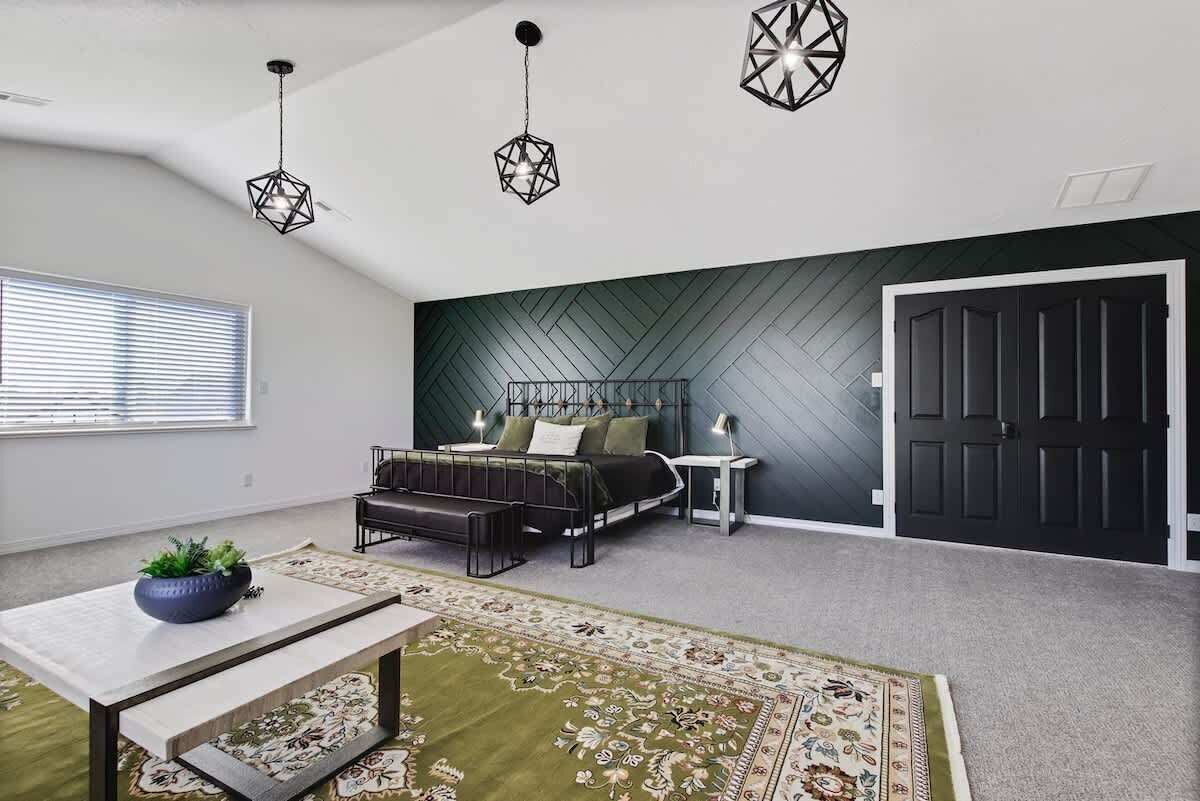 A bedroom with a bed, bedside tables, a desk, a chair, a window, and a door.