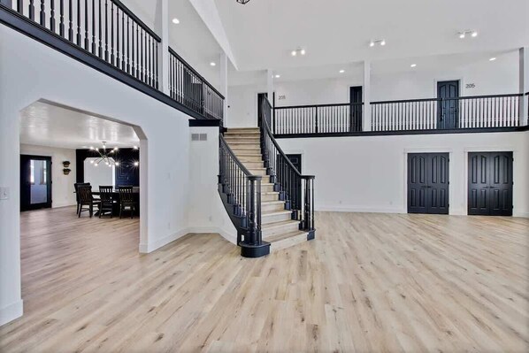 Un interior amplio con escaleras, suelo de madera y un comedor.