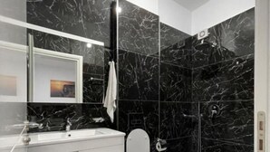 A modern bathroom with a marble vanity, a toilet, and a shower area. - Hotel Seadel (Ksamil)
