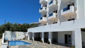 A modern multi-story building with a swimming pool, outdoor seating, and a clear blue sky. - Hotel Seadel (Ksamil)