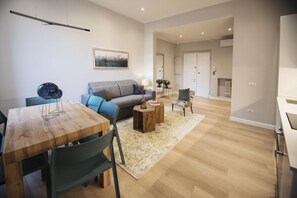 A modern living room with a wooden dining table, a grey sofa, and a coffee table. - Apartments Florence- Oblate Exclusive View	 (Firenze)