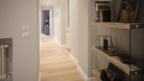 A hallway with wooden flooring, a glass display case, and a bookshelf with books and decorative items. - Apartments Florence- Oblate Exclusive View	 (Firenze)