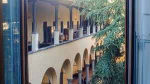 A courtyard with arches, columns, and a tree. - Apartments Florence- Oblate Exclusive View	 (Firenze)