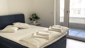 A neatly made bed with white linens, a small bedside table with a plant, and a view of the outside through a glass door. - Central luxury apartment close to Prater / Messe / WU (Leopoldstadt)