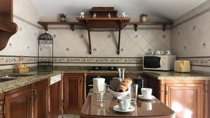 Een keuken met houten kastjes, een granieten aanrecht, een glazen tafel en een magnetron.