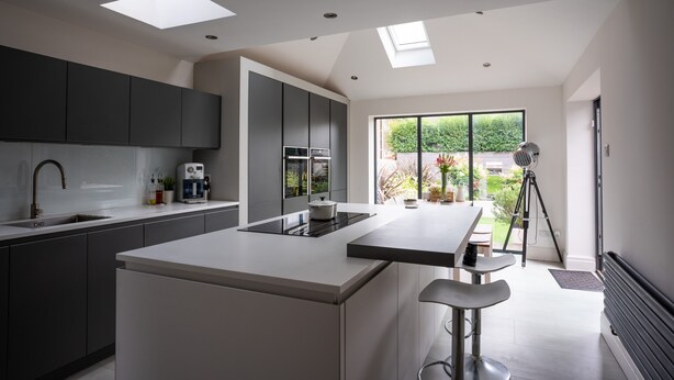A modern kitchen with a central island, dark cabinets, and a large window offering a view of the outdoors. - Contemporary Bright House 20 Min To Manc (Stockport)