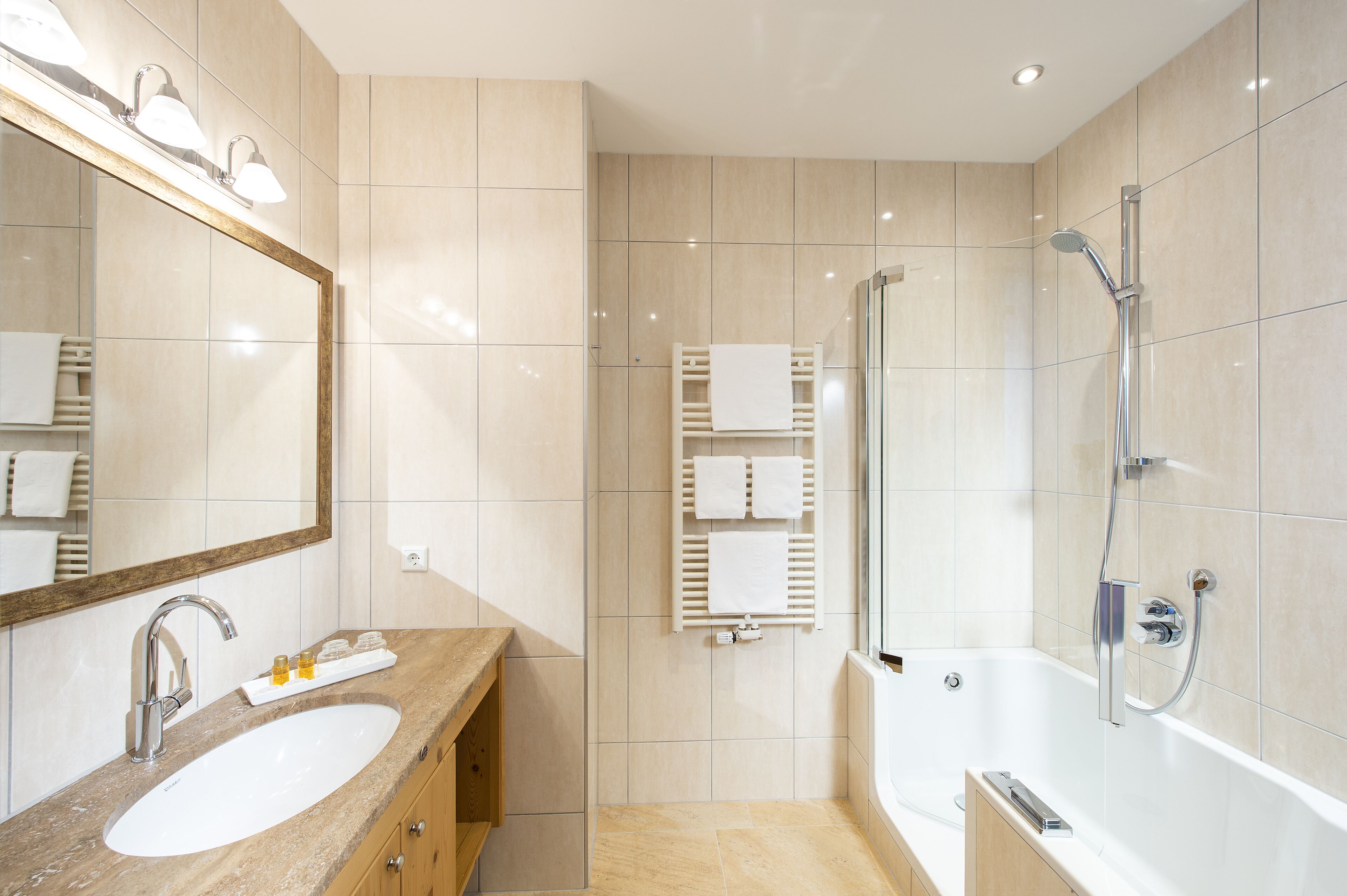 Een moderne badkamer met een grote spiegel, een wastafel, een douche en een bad.