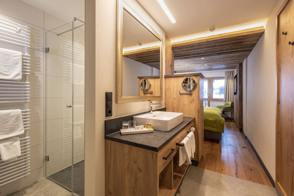 A modern bathroom with a glass shower, wooden vanity, and a large mirror.